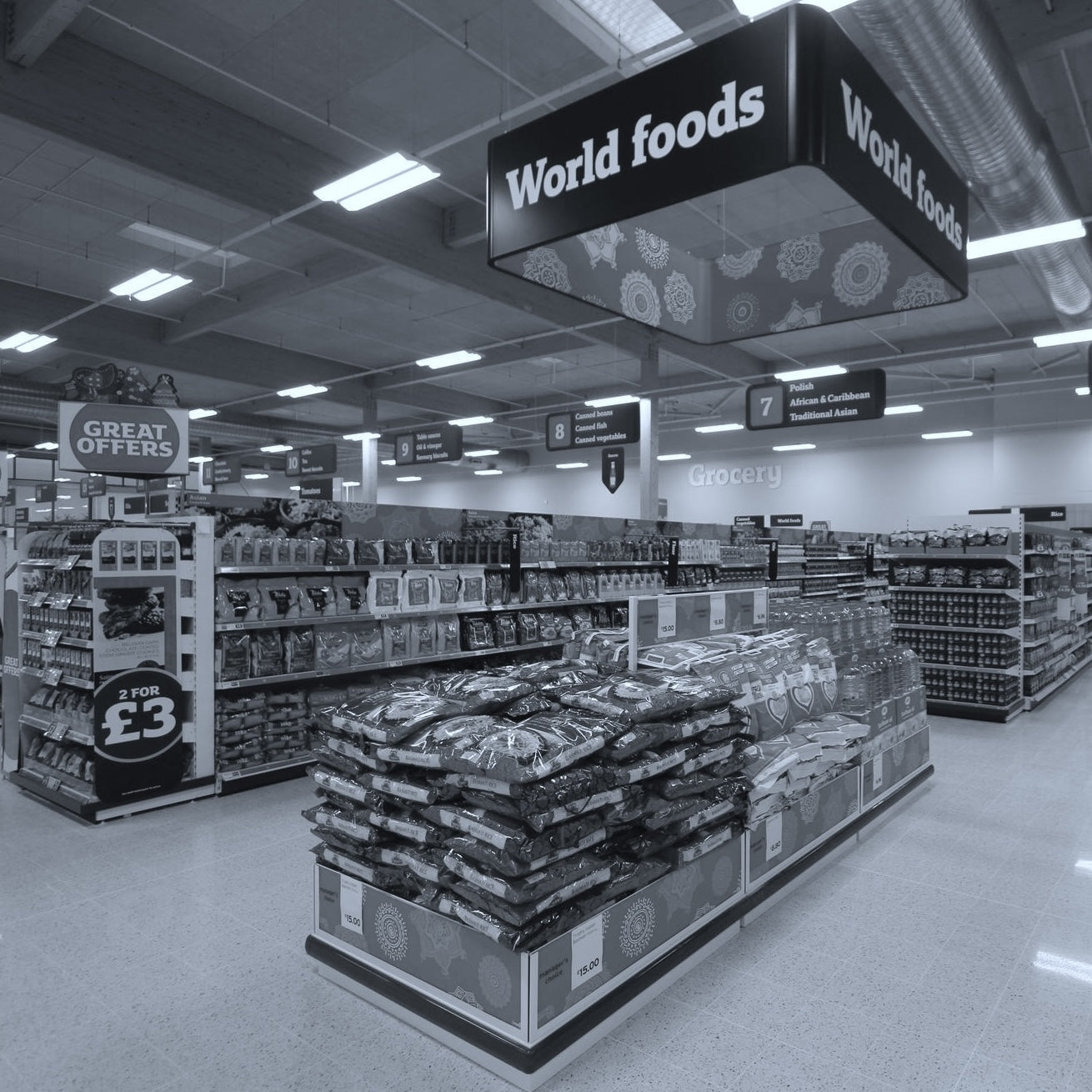 Supermarket aisle with 'World foods' sign and product displays.